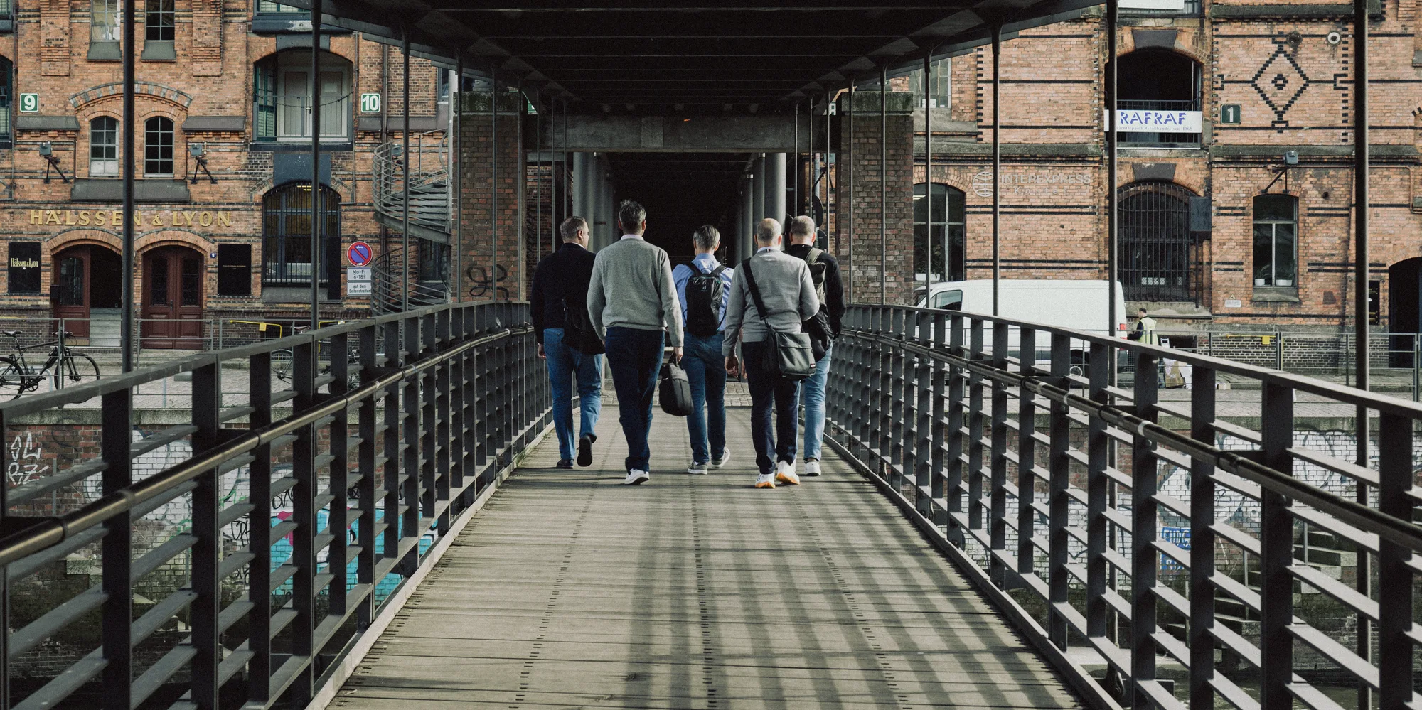 Five men walking away across a covered footbridge in the Speicherstadt