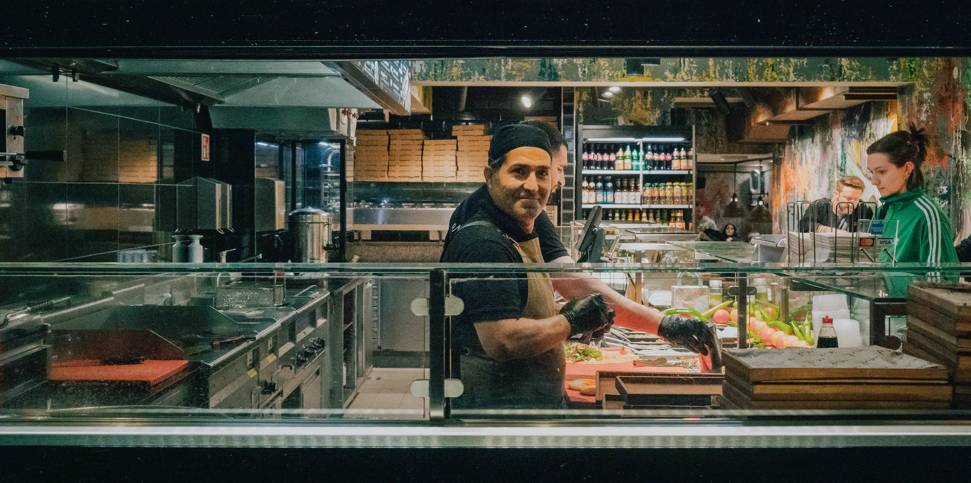 A man behind the counter of a kebab shop smiling at the camera