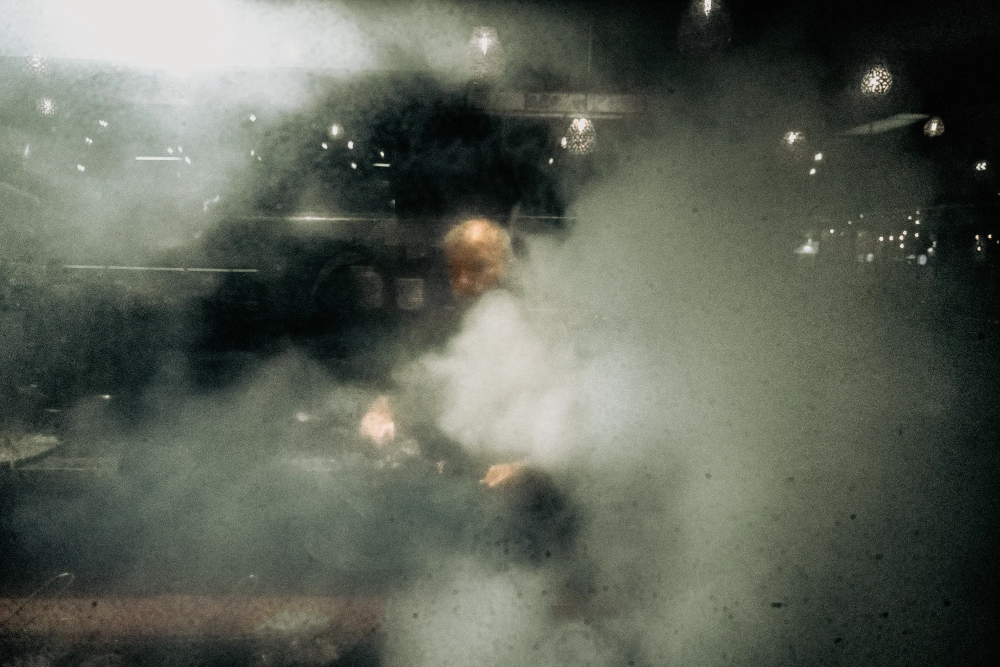 A cook seen through steam and glass in a dark kitchen