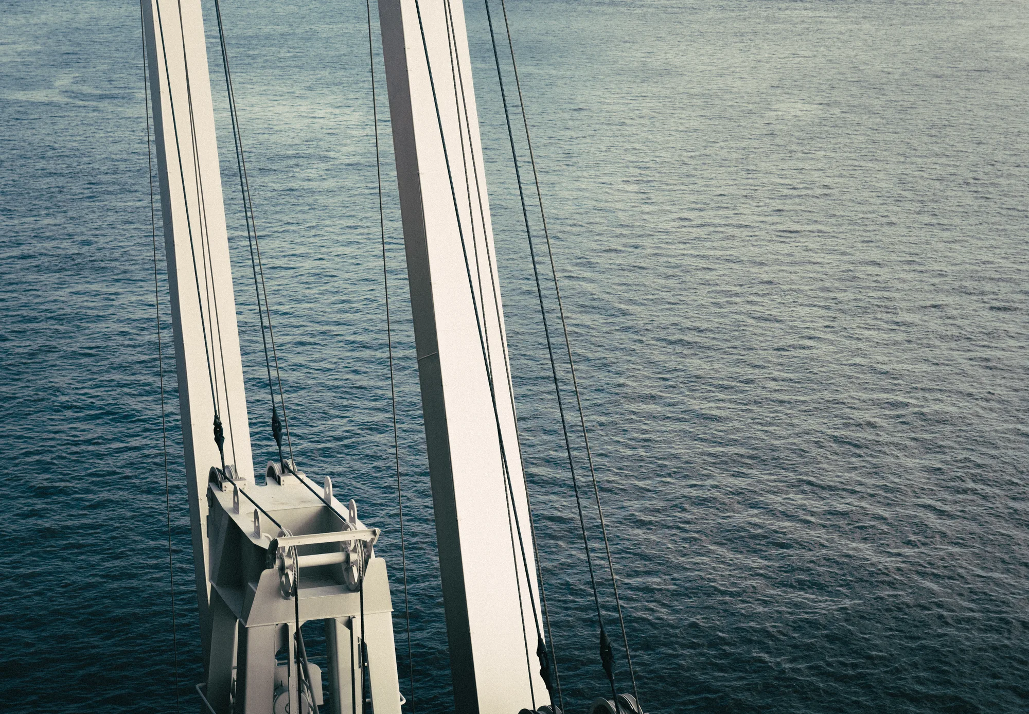 Looking straight down past white steel cables to dark water