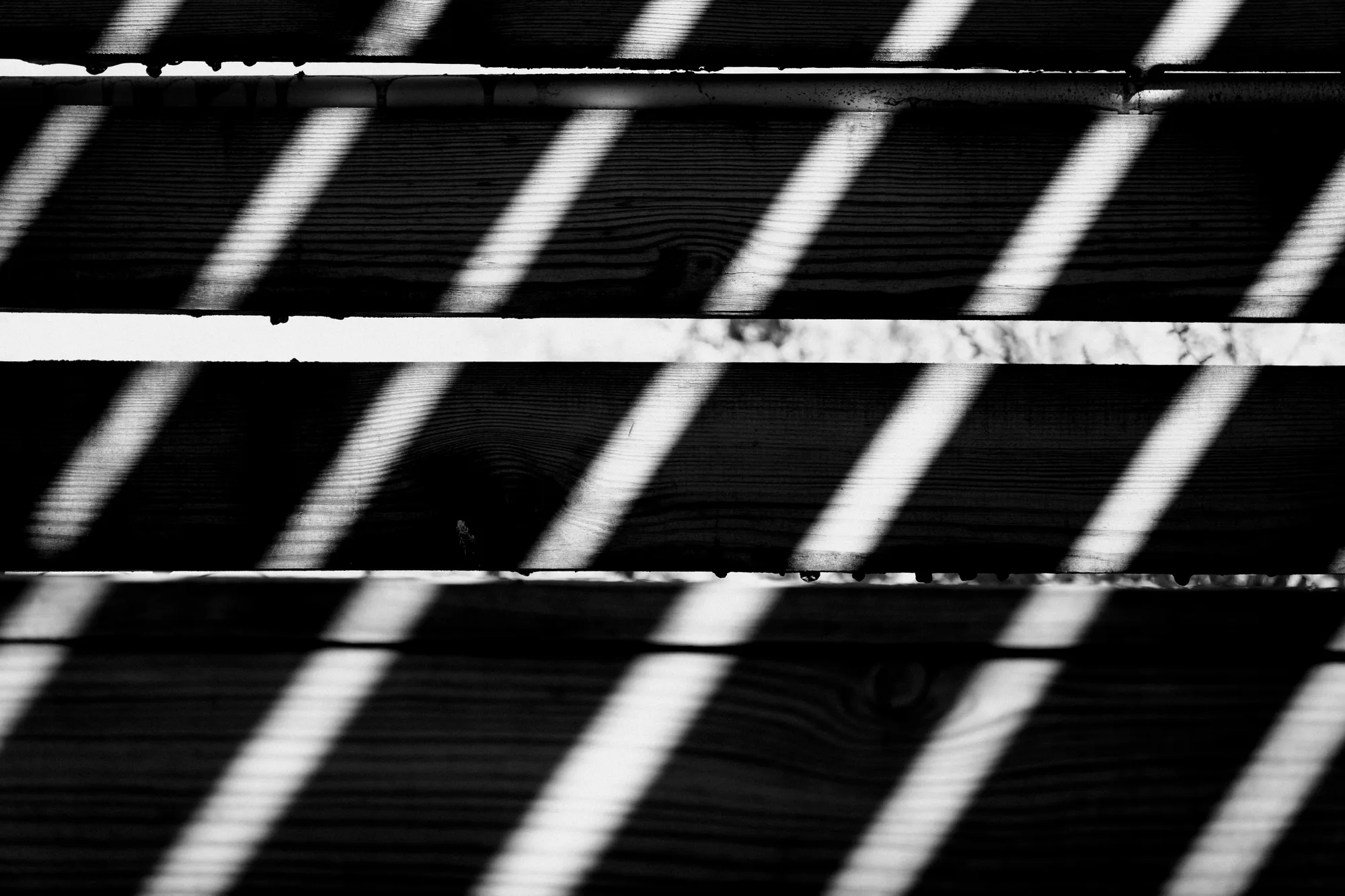 Diagonal bars of light falling across the slats of a wooden bench