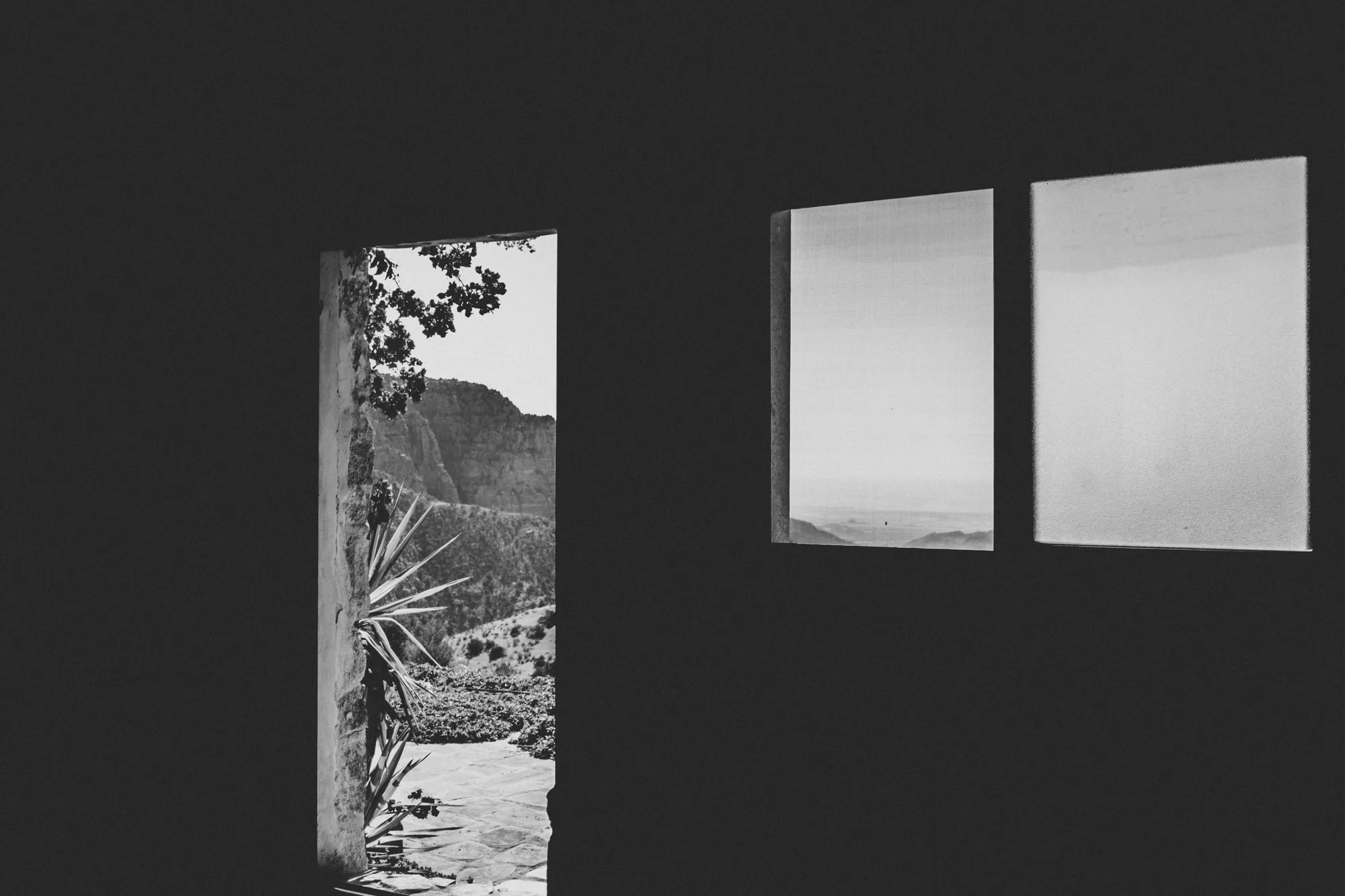 A dark room with a doorway and two windows looking out over the Dana valley