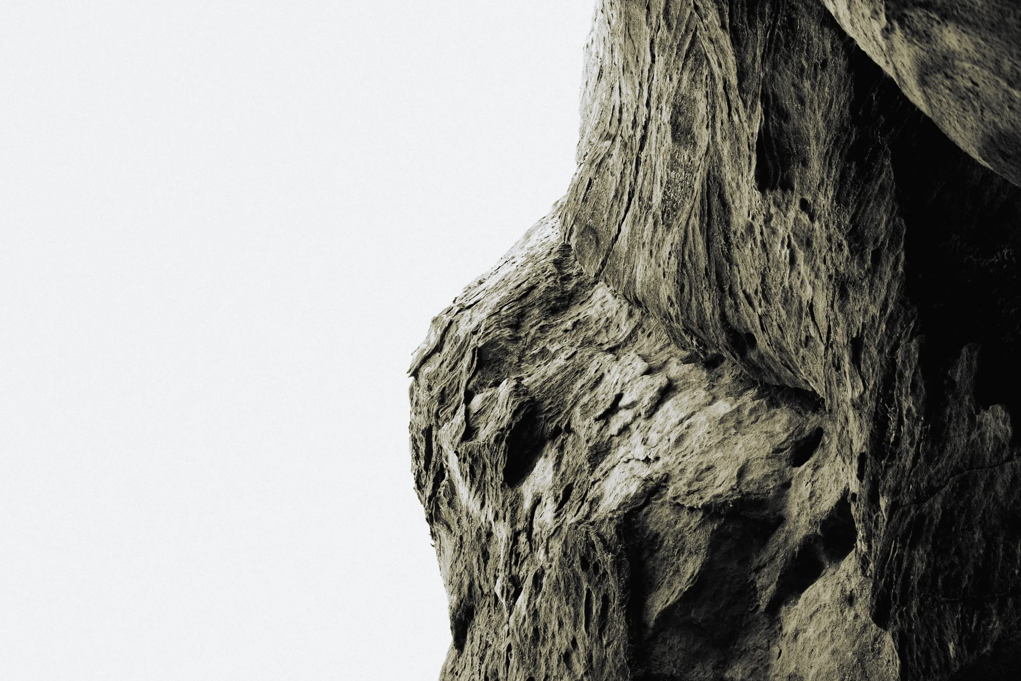 A weathered rock face against a white sky