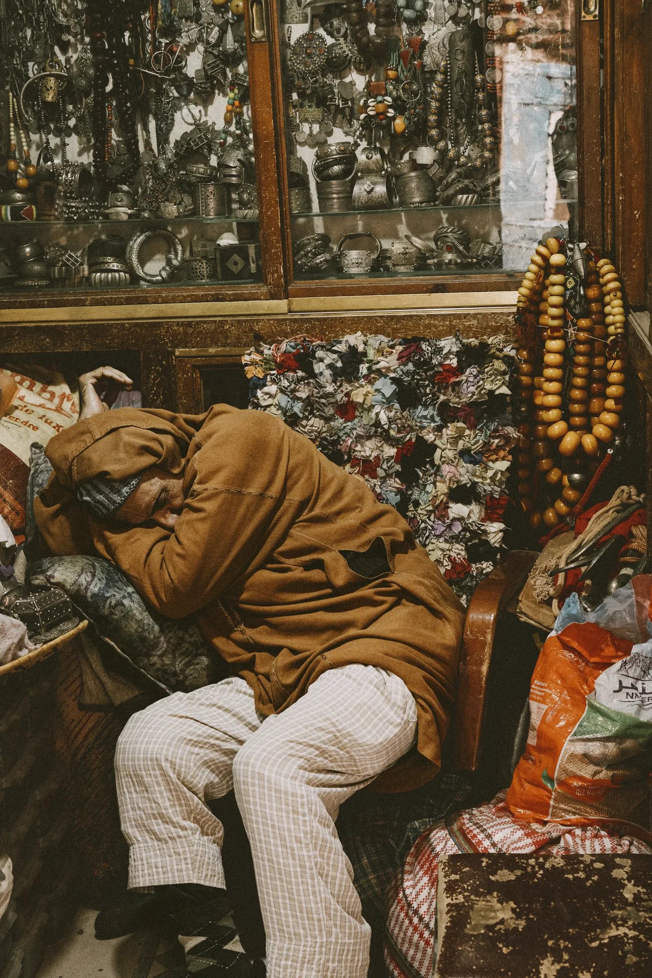 A man asleep in a chair in a crowded antiques shop