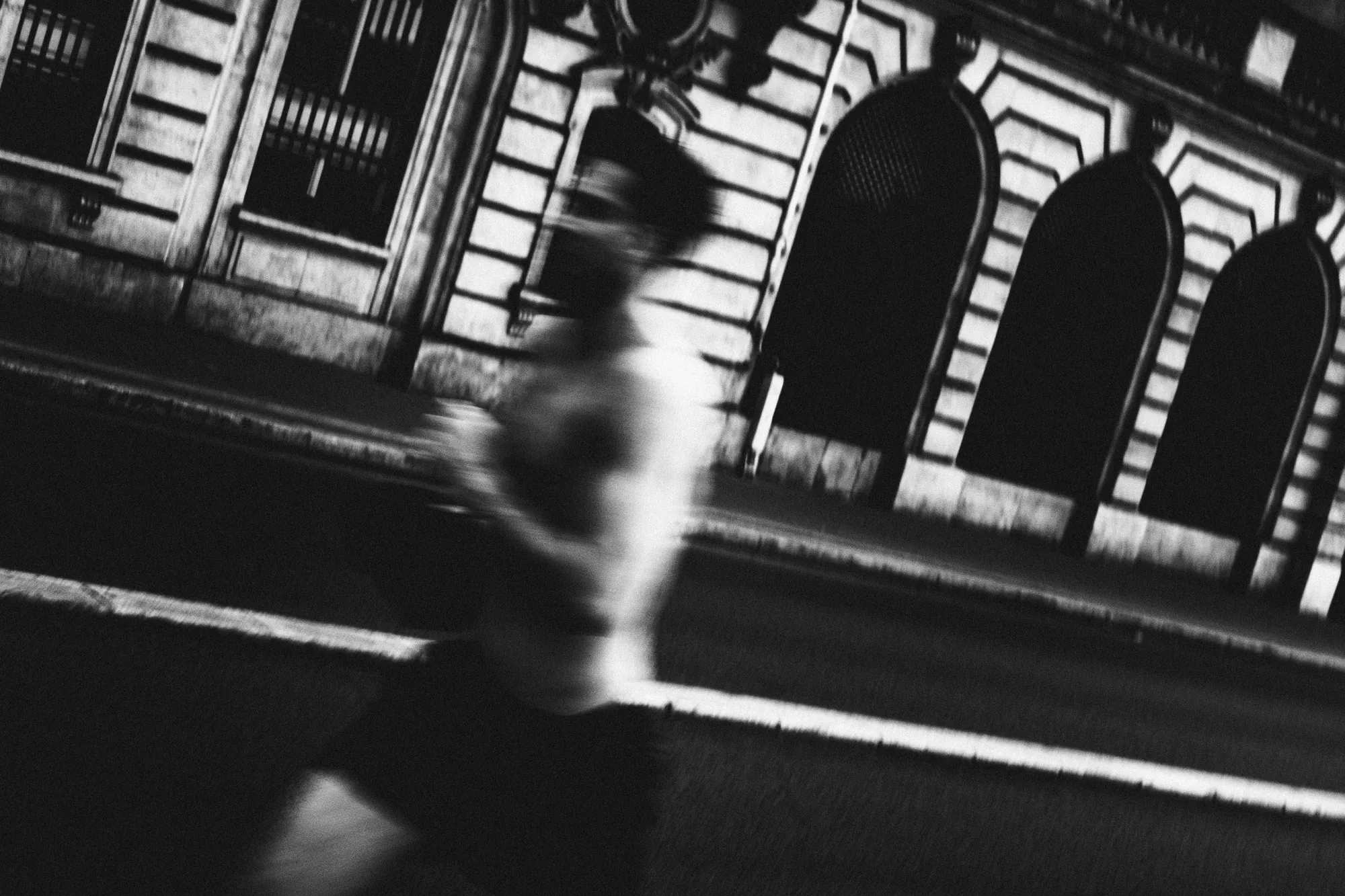 A figure running past arched windows, blurred with motion